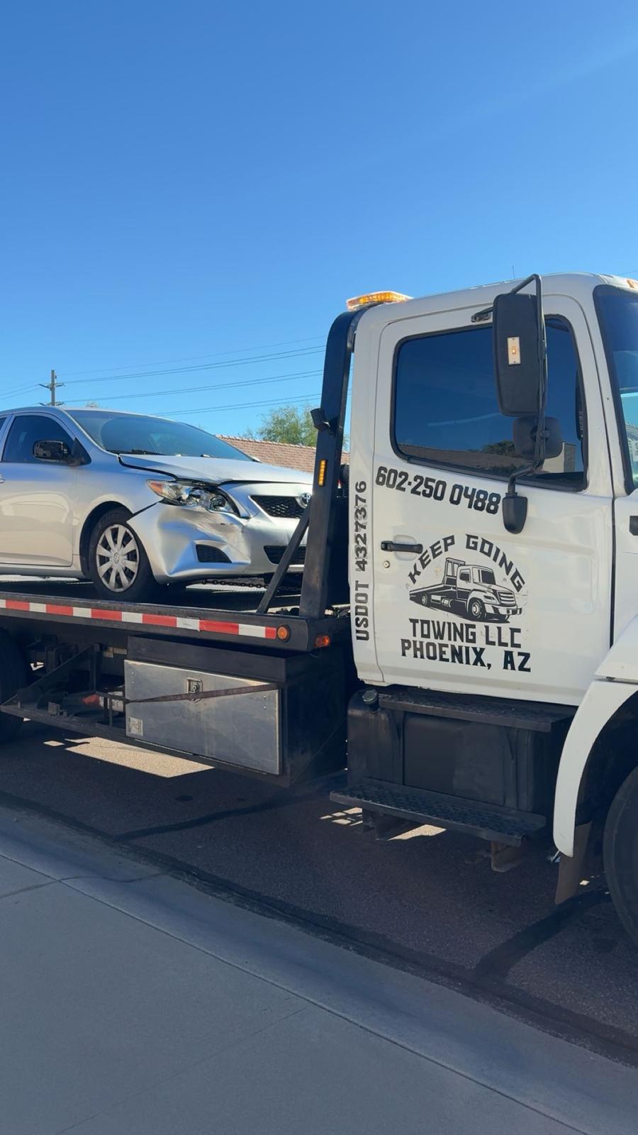 Keep Going flatbed tow truck transporting a car in Phoenix
